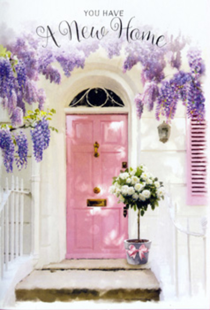 In this scene, a charming front door in Hemel Hempstead is transformed into a quiet celebration of home by flowers and soft colour. The door itself is painted a delicate pink, somewhere between blush and rose, with an even finish that reflects daylight in a muted, almost velvety way. Surrounding it, whitewashed walls create a clean backdrop, slightly textured to suggest an older property lovingly maintained, perhaps one of the homes you might find near the old town or along a residential lane off Leighton Buzzard Road. Draped over the doorway is a profusion of wisteria, its branches heavy with clusters of lavender-hued flowers. The blossoms hang in trailing garlands that frame the door like a natural curtain, each cluster comprised of many small petals that deepen in colour towards their tips. The way they fall suggests a gentle movement, as though a breeze might set them swaying and send soft floral fragrance across the step. At ground level, on a warm-toned stone threshold, rests a simple but stylish grey metal bucket, chosen with a florist's eye for understated elegance. Rising from the bucket is a full arrangement of white and creamy roses, layered and plush, each bloom turned slightly differently to create a natural, garden-like feel. Some petals fold back fully, others cup inward, hinting at their gradual opening. Among the roses, threads of soft green foliage weave through, some leaves smooth and oval, others slightly more feathery, adding whispers of texture and freshness. Tied around the bucket is a wide satin ribbon in a gentle blush pink, its bow loose and relaxed, with trailing ends that echo the downward lines of the wisteria above. The light in the image is soft and dappled, as if filtered through trees, casting patterned shadows onto the step and lower wall. It feels like a moment just before guests arrive to a housewarming in Hemel Hempstead, the flowers silently offering congratulations and an open-hearted welcome.